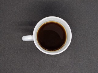 White cup with coffee. White cup of coffee top view. White cup of coffee on a black background top view.