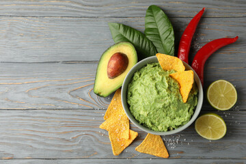 Concept of tasty eating with bowl of guacamole on wooden background, space for text