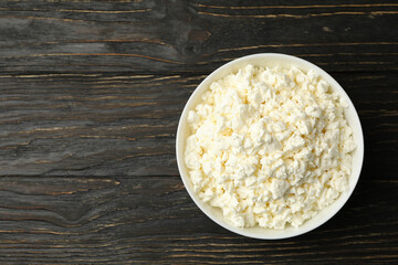 Bowl with fresh cottage cheese on wooden background