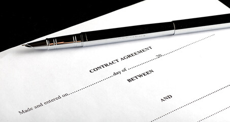 Close-up of silver pen on contract. Selective focus on top of pen.