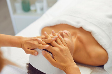 Woman getting professional face lifting massage while relaxing in modern spa salon