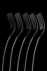 Artistic place setting photo of five standing forks in a dark field arrangement.