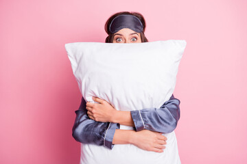 Photo portrait of girl hugging pillow hiding isolated on pastel pink colored background