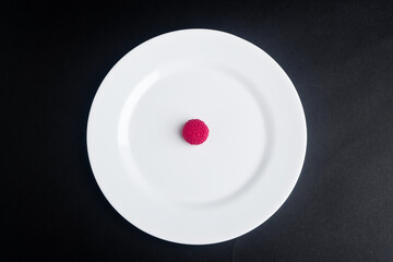 White plate with red jelly bean, black background, Spain