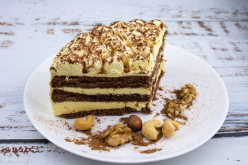 sweet nut dessert, chocolate puff cake, tiramisu, striped honey cake, a piece of cream cake on a white plate with nuts