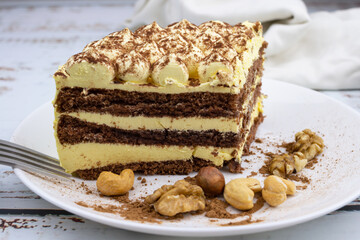sweet nut dessert, chocolate puff cake, tiramisu, striped honey cake, a piece of cream cake on a white plate with nuts