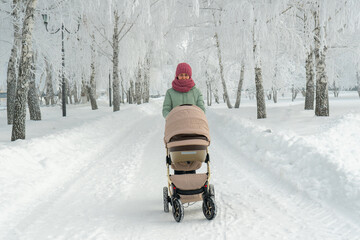 Mom with a stroller in a city park in winter