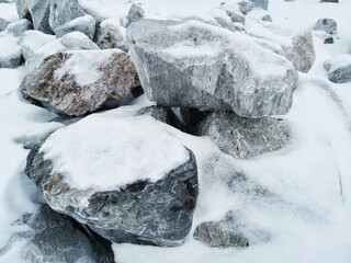 Stones covered with snow near the frozen water in Kvaloya, Tromso, Norway