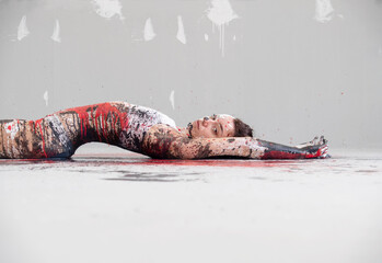 young and sexy seductive Woman in underwear, sportswear, artistically abstract painted with white, red and black paint, lying on the colorful painted floor in the studio, copy space.