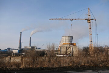 Fototapeta na wymiar Almaty, Kazakhstan - 02.04.2021 : Cooling tower, Smoking chimneys and tower crane to the district heating