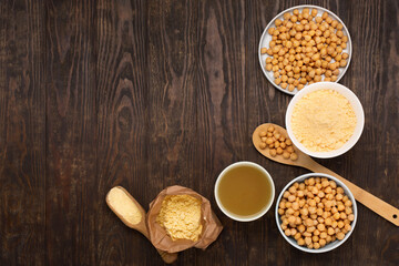 Cooked Chickpeas, aquafaba, chickpea flour on dark wooden background.