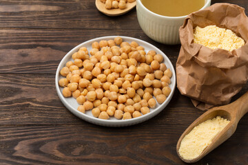 Cooked Chickpeas, aquafaba, chickpea flour on dark wooden background.