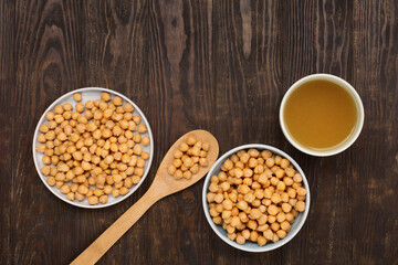 Cooked Chickpeas and chickpea aquafaba on dark wooden background.