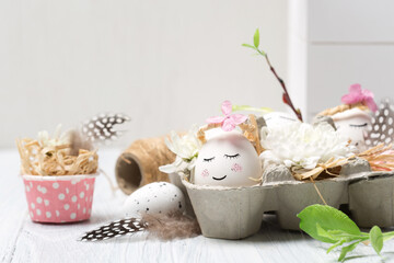 Zero waste Easter concept with white cute eggs, green tree branches, quail feathers and spring flowers on white wooden background.