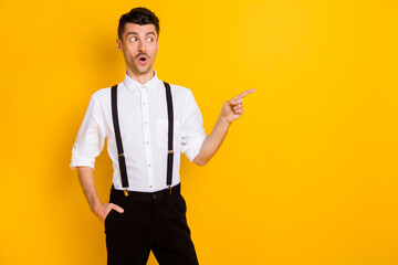 Photo portrait of amazed shocked man pointing finger blank space advising isolated on bright yellow color background