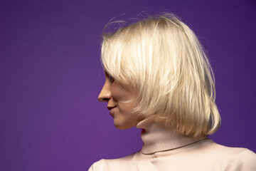 Studio portrait of a smiling blonde woman 25-30 years old on a color background, close-up, selective focus.