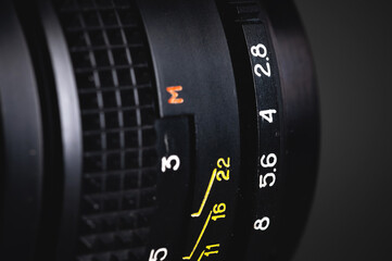 A close-up of the focus ring and aperture of a hand-held old lens. Photo background