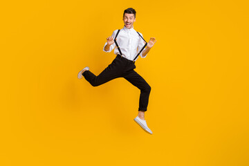 Fototapeta na wymiar Full body photo of cheerful person hands playing with suspenders jump high isolated on yellow color background
