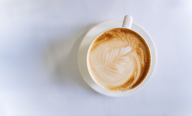Top view on a cup of coffee. Coffee with a beautiful pattern on top of a white table