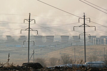 Almaty, Kazakhstan - 02.04.2021 : Power lines against the background of smoking cooling towers of a...