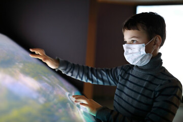Boy in medical mask using touch screen