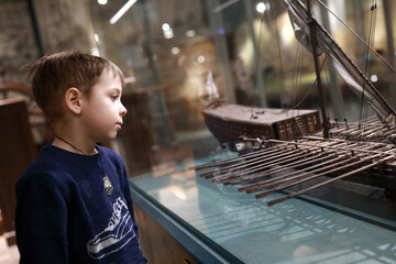 Child examines model of sailboat