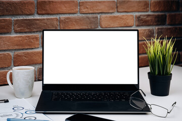 Fototapeta premium Working desk with blank screen laptop. White computer monitor on the working table. Mockup concept