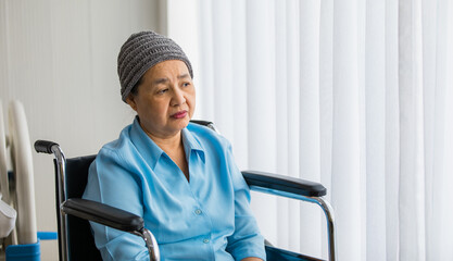 Older Asian woman patient covered the head with clothes effect from chemo treatment in cancer cure...