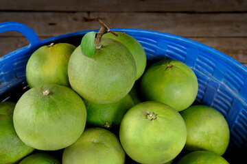 Green pomelo fruit in basket.