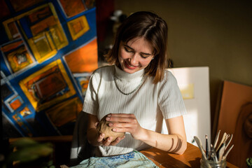 young artist moulding raw clay in art studio. Girl molds from clay sculpture in the artist's...