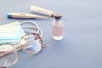 Medicines, medical masks, glasses on a blue background, space for text-the concept of providing medical care to the elderly