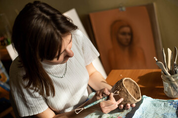 young artist moulding raw clay in art studio. Girl molds from clay sculpture in the artist's studio. Business woman at her pottery store
