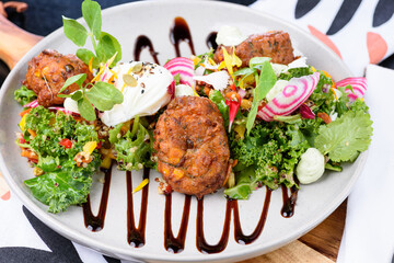 Zucchini and Halloumi Corn Fritters featuring caramelized balsamic and mint ricotta yoghurt with a green super salad and a light pomegranate dressing