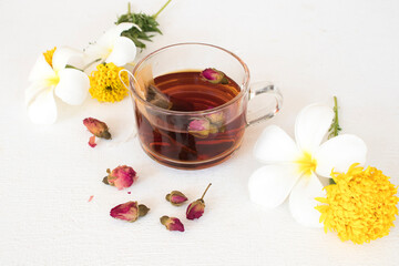 herbal healthy drinks hot tea rose cocktail water with flowers frangipani ,marigold ,ylang ylang arrangement flat lay style on background wooden white 