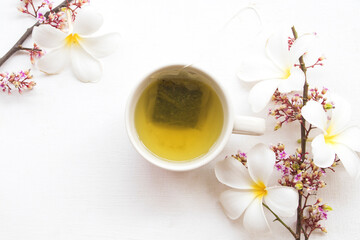 Obraz na płótnie Canvas herbal health drinks hot green tea with flowers arrangement flat lay style on background white 