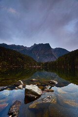 a clear lake with trees and mountains