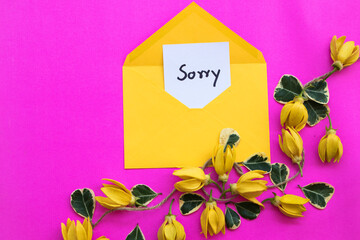 sorry message card handwriting with yellow flowers ylang ylang in envelope arrangement flat lay...