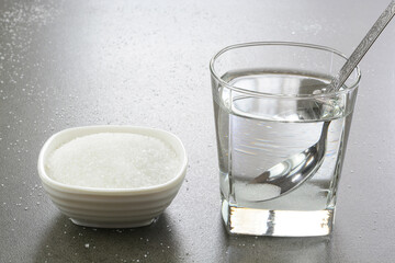 Sugar water in a glass cup and heap of sugar in a bowl. Sugar water is instant energy sports drink,...