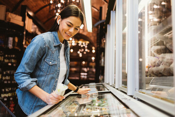 Smiling young woman shopping food at grocery store