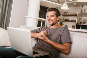 Young man showing gesture in sign language, using laptop.
