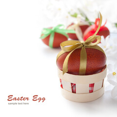 Red Easter egg with gold ribbon in a basket