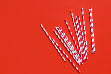 Striped and dotted paper drinking straws on red background top view