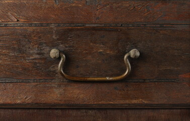 Antique metal drawer pull, cabinet handle on wooden background and texture