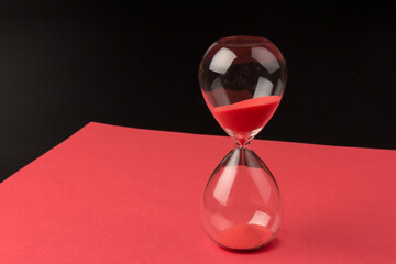 Crystal hourglass on black and red background as a concept of passing time for business term,...