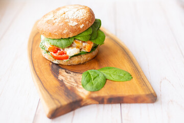 Burger with king prawn, feta cheese and vegetables, on a wooden board