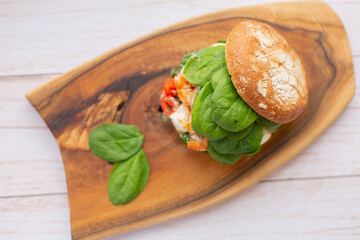 Burger with king prawn, feta cheese and vegetables, on a wooden board