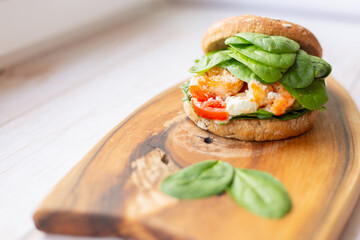 Burger with king prawn, feta cheese and vegetables, on a wooden board
