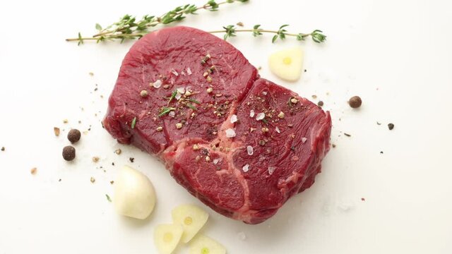 close up of rotating spicy raw beef steak meat on white background, top view zoom in