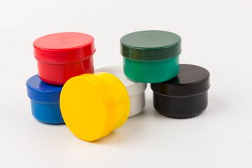 Closed plastic jars with paint of different colors for children's creativity on white background....