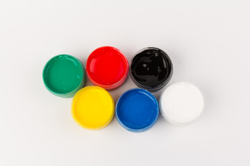 Plastic jars with paint of different colors for children's creativity on white background. Paint bottles for art